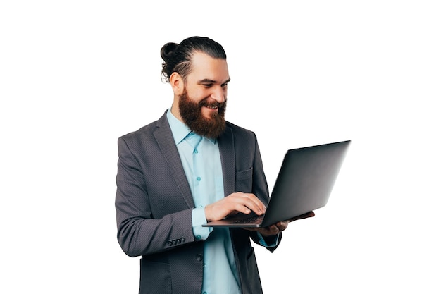 Retrato de un hombre guapo con una chaqueta y escribiendo en la computadora portátil que sostiene