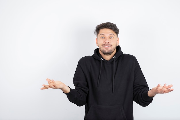 Retrato de hombre guapo confundido encogiéndose de hombros aislado sobre fondo blanco.