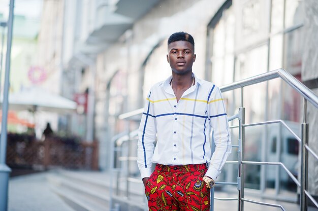 Retrato de hombre guapo elegante modelo afroamericano en pantalones rojos y camisa blanca.