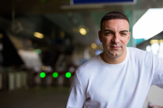 Retrato de hombre guapo en la estación de tren del cielo en la ciudad