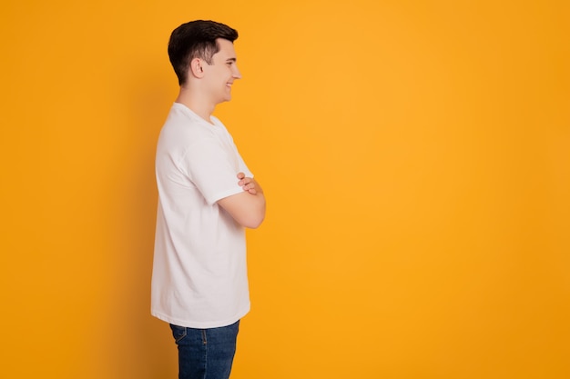 Retrato de hombre guapo feliz cruzando las manos mirar espacio vacío aislado sobre fondo amarillo