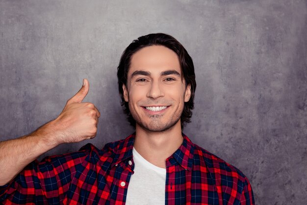 Foto retrato de hombre guapo feliz mostrando el pulgar hacia arriba