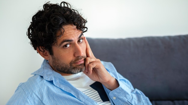 Retrato de hombre guapo y fresco con una camisa y sentado en un sofá en el interior de la casa. Apuesto hombre caucásico en el sofá de la casa. Modelo masculino guapo.