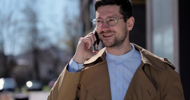 Retrato de hombre guapo con gafas hablando por teléfono en la calle Hombre de negocios hablando por teléfono inteligente en la calle Gadget al aire libre usando el concepto