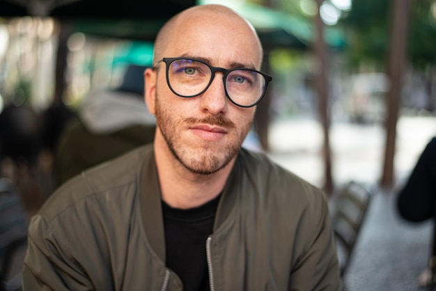 Retrato de un hombre guapo con gafas en la terraza de un restaurante por la noche