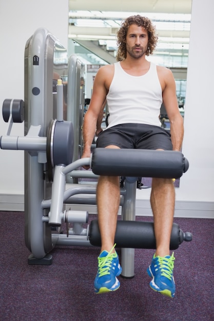 Foto retrato de hombre guapo haciendo ejercicios de piernas en el gimnasio