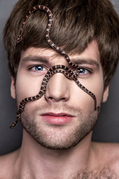Retrato de un hombre guapo joven con la serpiente en su cara