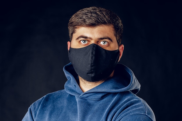 Retrato de hombre guapo con máscara negra médica en la cara durante el cierre de la epidemia de virus