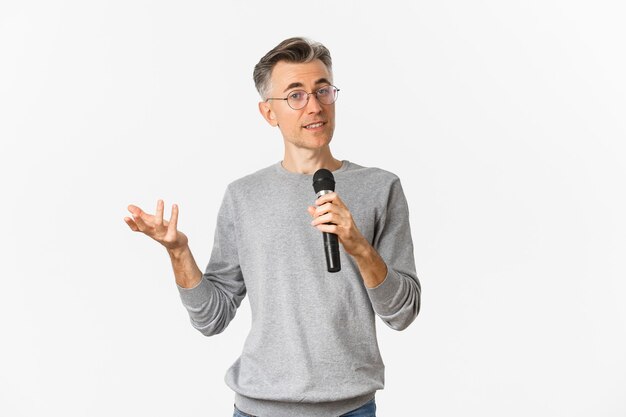 Retrato de hombre guapo de mediana edad con gafas y suéter gris, haciendo discurso