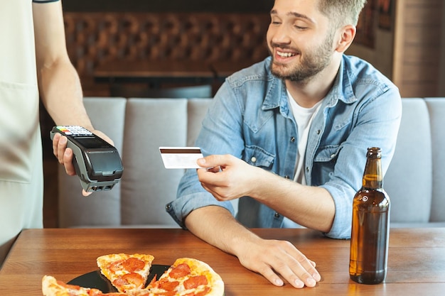 Retrato de hombre guapo pagando con tarjeta de crédito en el café