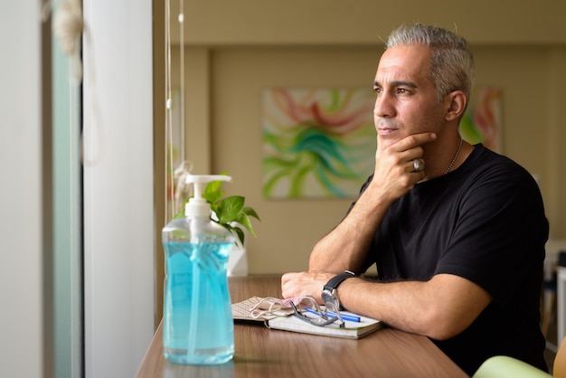 Retrato de hombre guapo persa con canas en la biblioteca dentro del edificio moderno