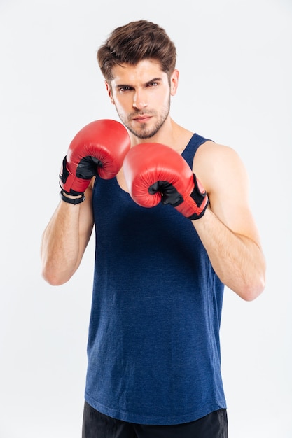 Retrato de un hombre guapo de pie con guantes de boxeo aislado sobre un fondo gris