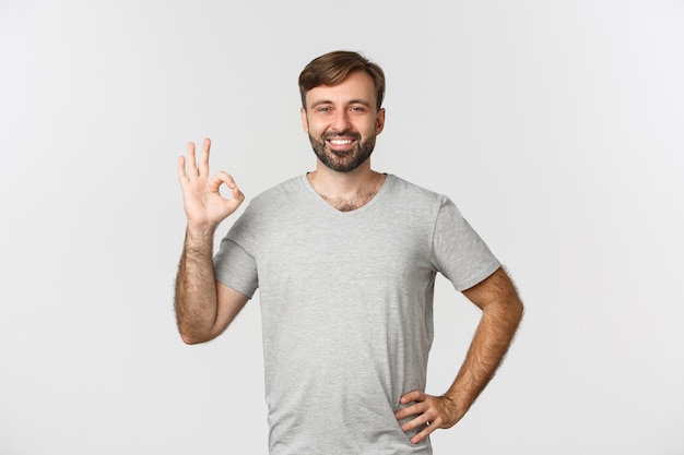 Retrato de hombre guapo sonriente en camiseta gris casual