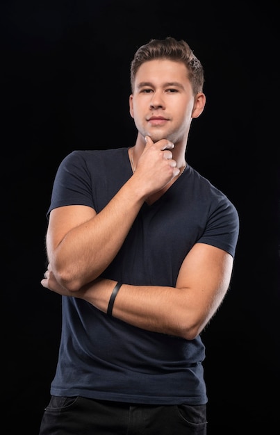 Retrato de hombre guapo sonriente posando en estudio sobre un fondo negro