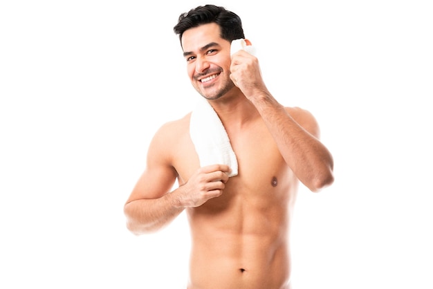 Retrato de un hombre guapo sonriente que usa una toalla blanca para limpiarse aislado de fondo blanco