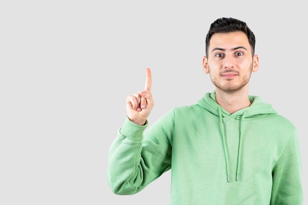 Retrato de hombre guapo en sudadera con capucha de pie y apuntando