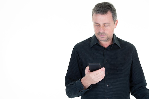 Retrato de hombre guapo texting mirando sosteniendo teléfono celular móvil en fondo blanco.