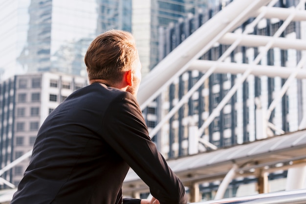 Retrato de hombre guapo en traje negro de pie al aire libre