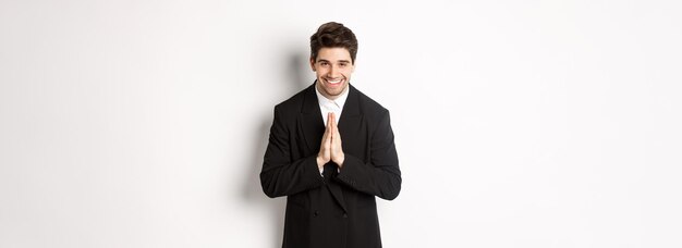 Foto retrato de un hombre guapo en traje negro siendo agradecido diciendo gracias y inclinándose cortésmente persona