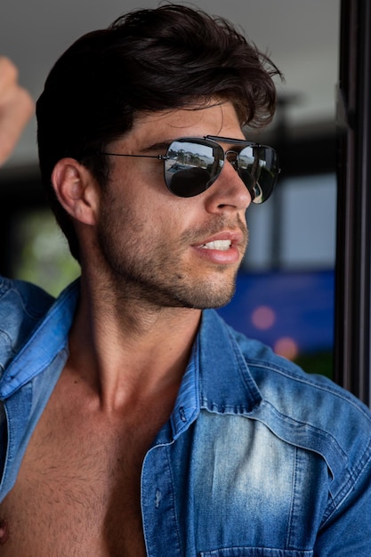 retrato de un hombre, hombre guapo con gafas de sol, camisa abierta mirando hacia un lado