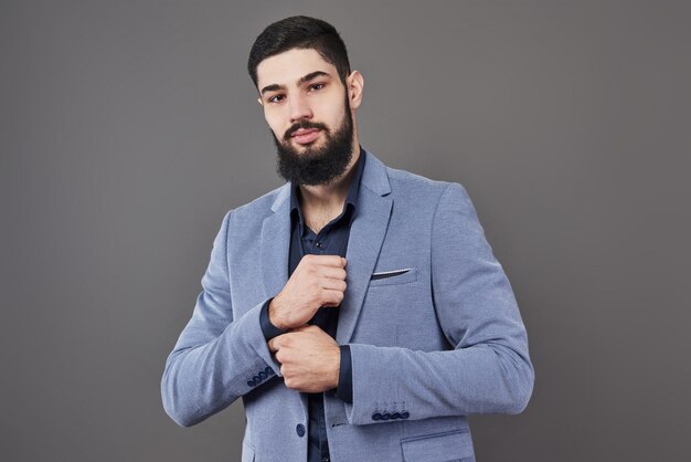 Retrato de hombre independiente con barba en pie de chaqueta en gris