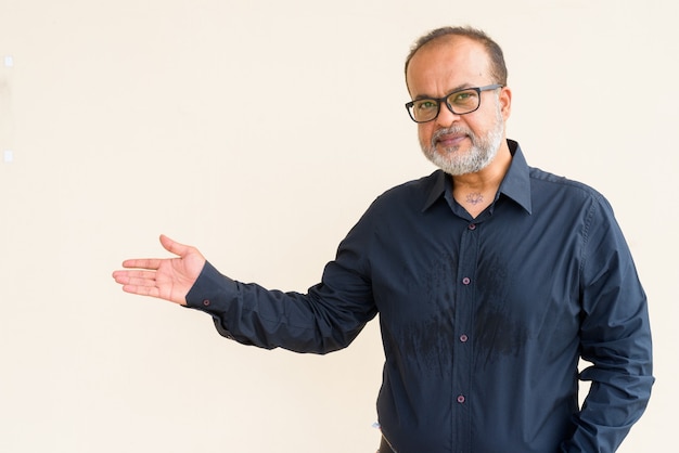 Foto retrato de hombre indio guapo con barba gris contra la pared lisa