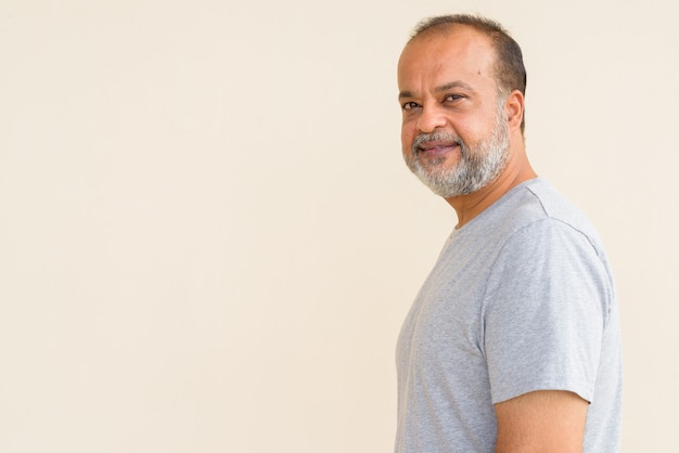 Foto retrato de hombre indio guapo con barba gris contra la pared lisa