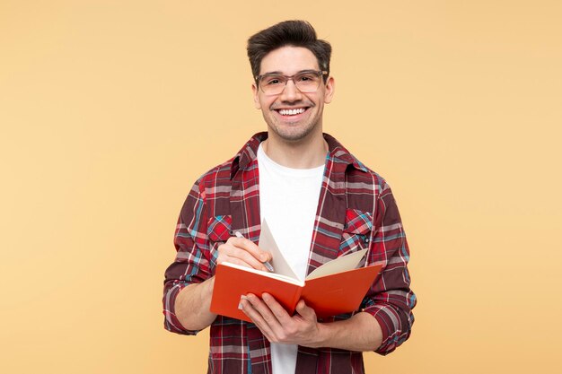 Retrato de un hombre inteligente y alegre con gafas sosteniendo un libro y una pluma