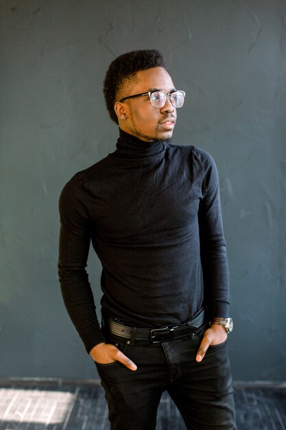 Retrato del hombre joven del ajuste con la construcción muscular que se opone a fondo negro. Modelo de fitness afroamericano.