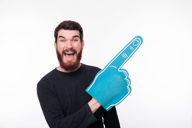 Retrato de hombre joven apuntando con espuma de dedo de ventilador en copyspace