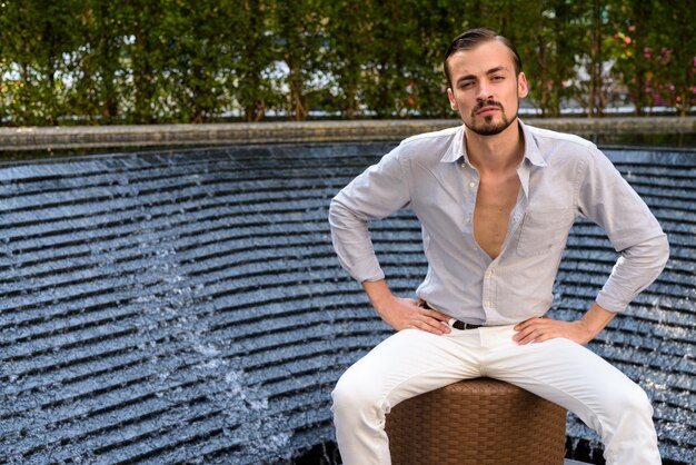 Retrato de hombre joven con barba sentado al aire libre