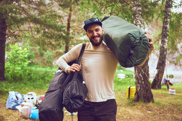 Retrato de un hombre joven y barbudo en la naturaleza. El concepto de expedición, aventura y vida de campamento.