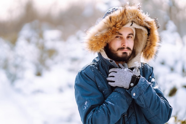 Retrato de hombre joven en el bosque de invierno cubierto de nieve Concepto de viajes y personas de Navidad de temporada