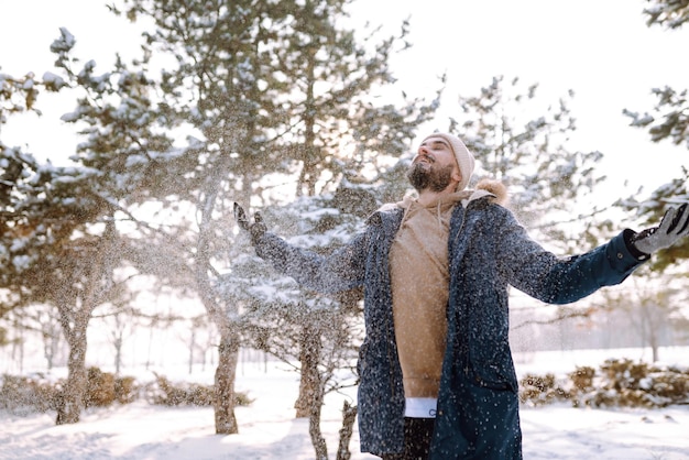 Retrato de hombre joven en el bosque de invierno cubierto de nieve Concepto de viajes y personas de Navidad de temporada