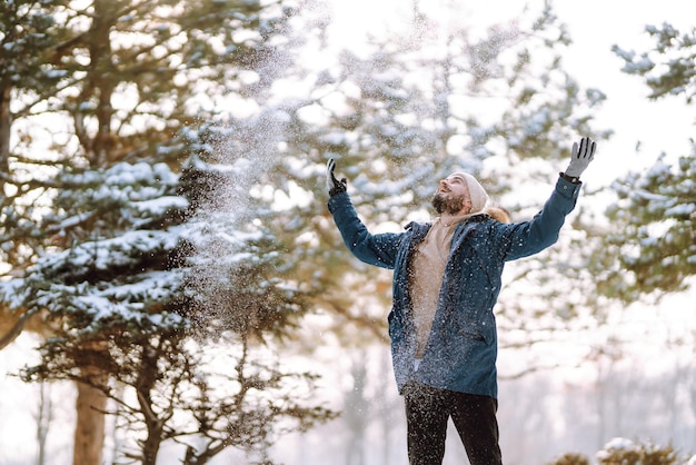 Retrato de hombre joven en el bosque de invierno cubierto de nieve Concepto de viajes y personas de Navidad de temporada