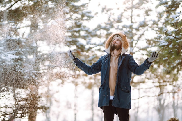 Retrato de hombre joven en el bosque de invierno cubierto de nieve Concepto de viajes y personas de Navidad de temporada