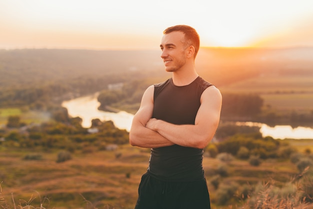 Retrato de un hombre joven con los brazos cruzados al atardecer.