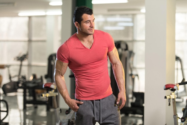 Retrato de un hombre joven en buena forma física en camiseta rosa que muestra su cuerpo bien entrenado Muscular atlético culturista modelo de fitness posando después de los ejercicios