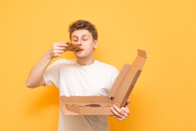 Retrato de un hombre joven con una camiseta blanca de pie sobre un amarillo