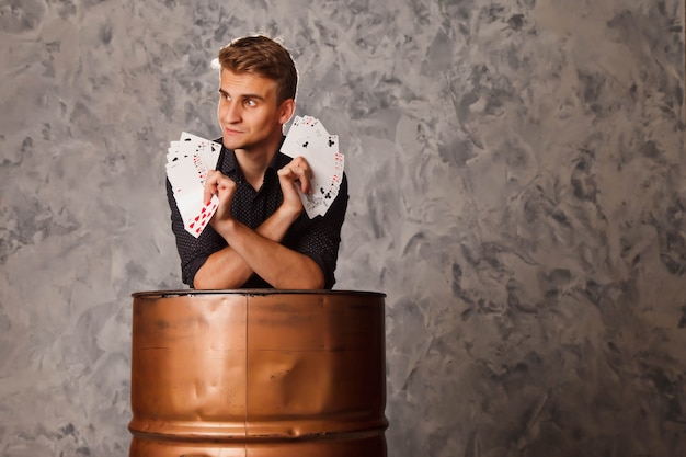 Retrato de hombre joven con cartas de juego de barril. chico guapo muestra trucos con tarjeta.