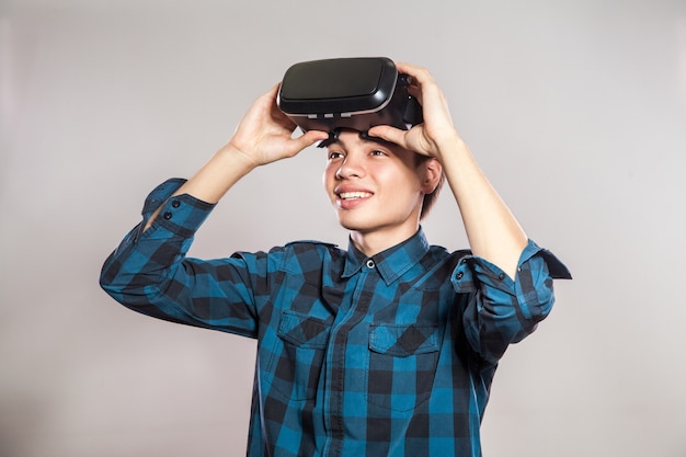 Retrato de hombre joven con casco de realidad virtual. interior, aislado sobre fondo gris.