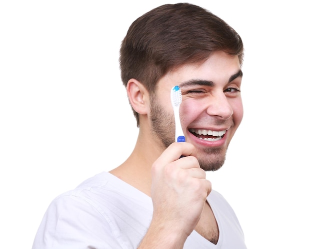 Retrato de hombre joven con cepillo de dientes en la mano aislado en blanco