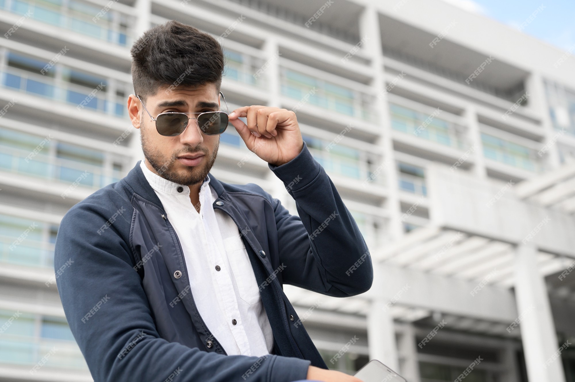 Retrato de hombre joven con elegantes gafas de sol posando junto a un edificio moderno Foto Premium