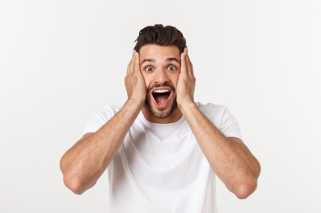 Retrato del hombre joven con la expresión facial chocada, aislado sobre blanco.