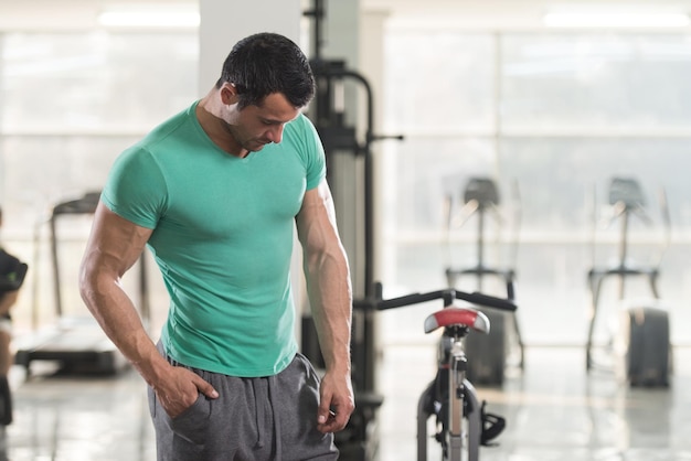 Retrato de un hombre joven físicamente apto en camiseta que muestra su cuerpo bien entrenado Muscular atlético culturista modelo de fitness posando después de los ejercicios