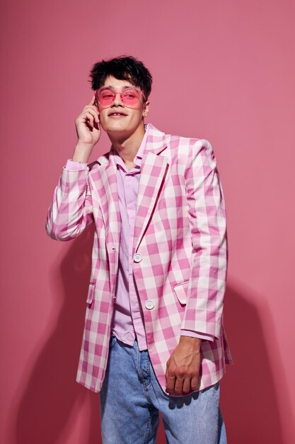 Retrato de un hombre joven en gafas rosas chaqueta rosa posando estudio fondo rosa inalterado