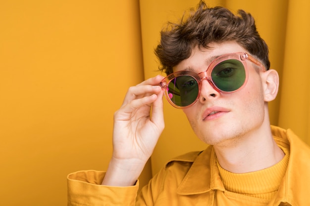 Retrato de hombre joven con gafas de sol en un escenario amarillo