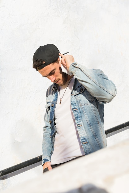 Foto retrato de un hombre joven con gorra y una chaqueta vaquera.