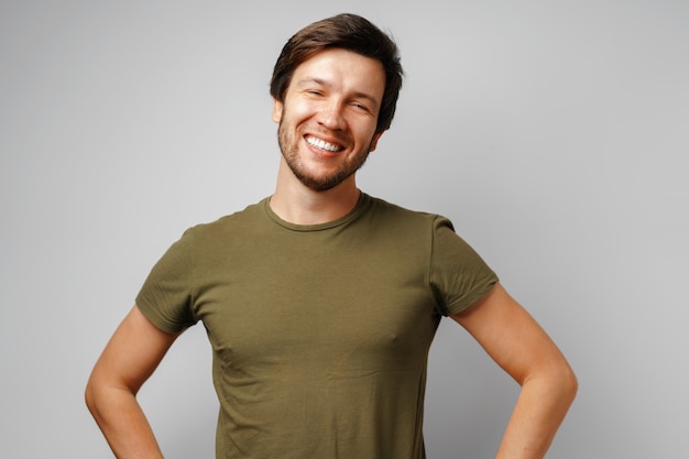 Retrato de hombre joven guapo sonriendo sobre fondo gris