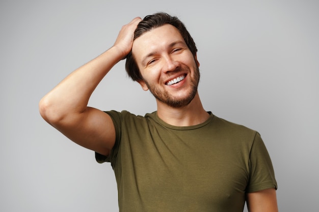 Retrato de hombre joven guapo sonriendo sobre fondo gris